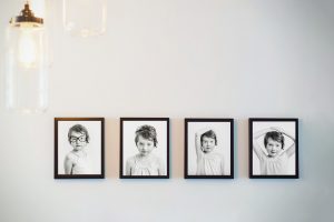an image of a line of four framed black and white portraits hung on a wall