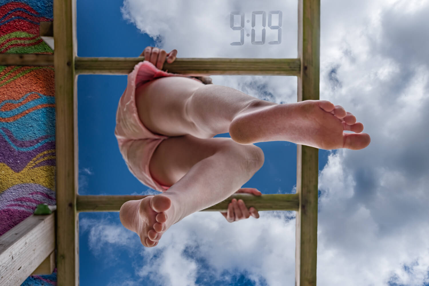 view of child's legs from below as they hang on climbing frame