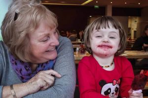 grandmother looks at grandchild with sticky face from a lolly