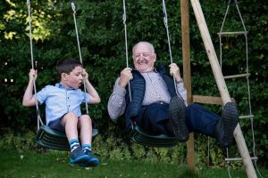 grandfather and grandson side by side on a swing set