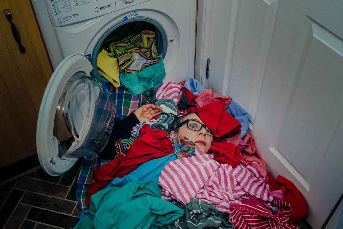 image of photographer swamped under pile of clothes maximum color