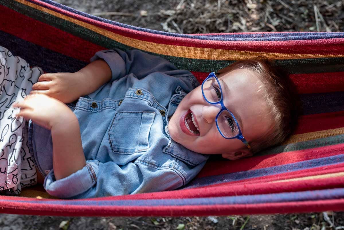 portrait of young boy laughing in a hammock