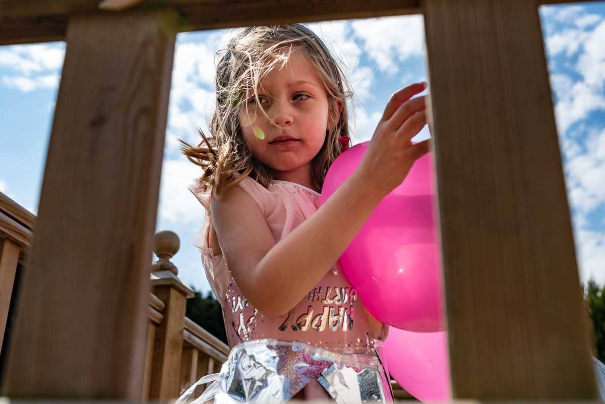 environmental portrait of a child with a pink balloon