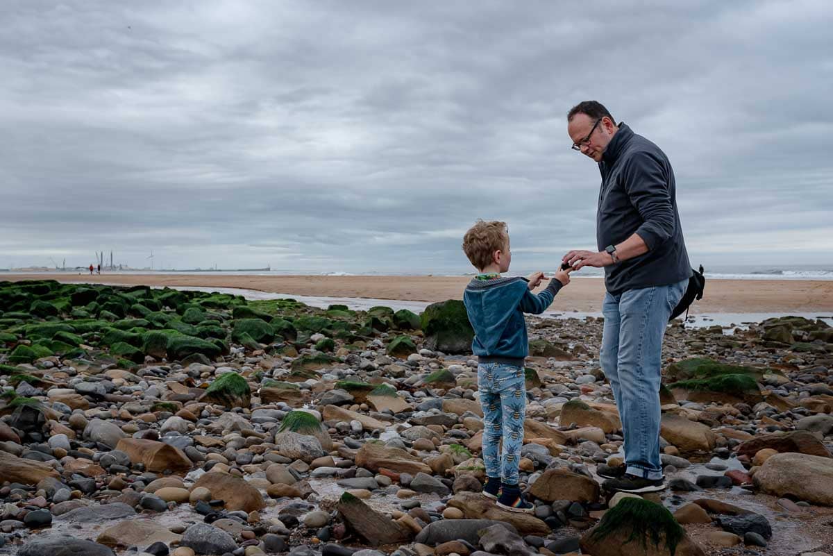 documentary family photographer captures father and son on a rocky northumberland beach