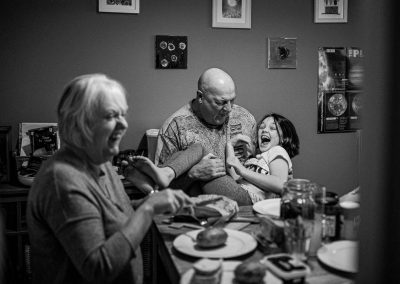 black and white documentary image of a meal with grandparents laughing