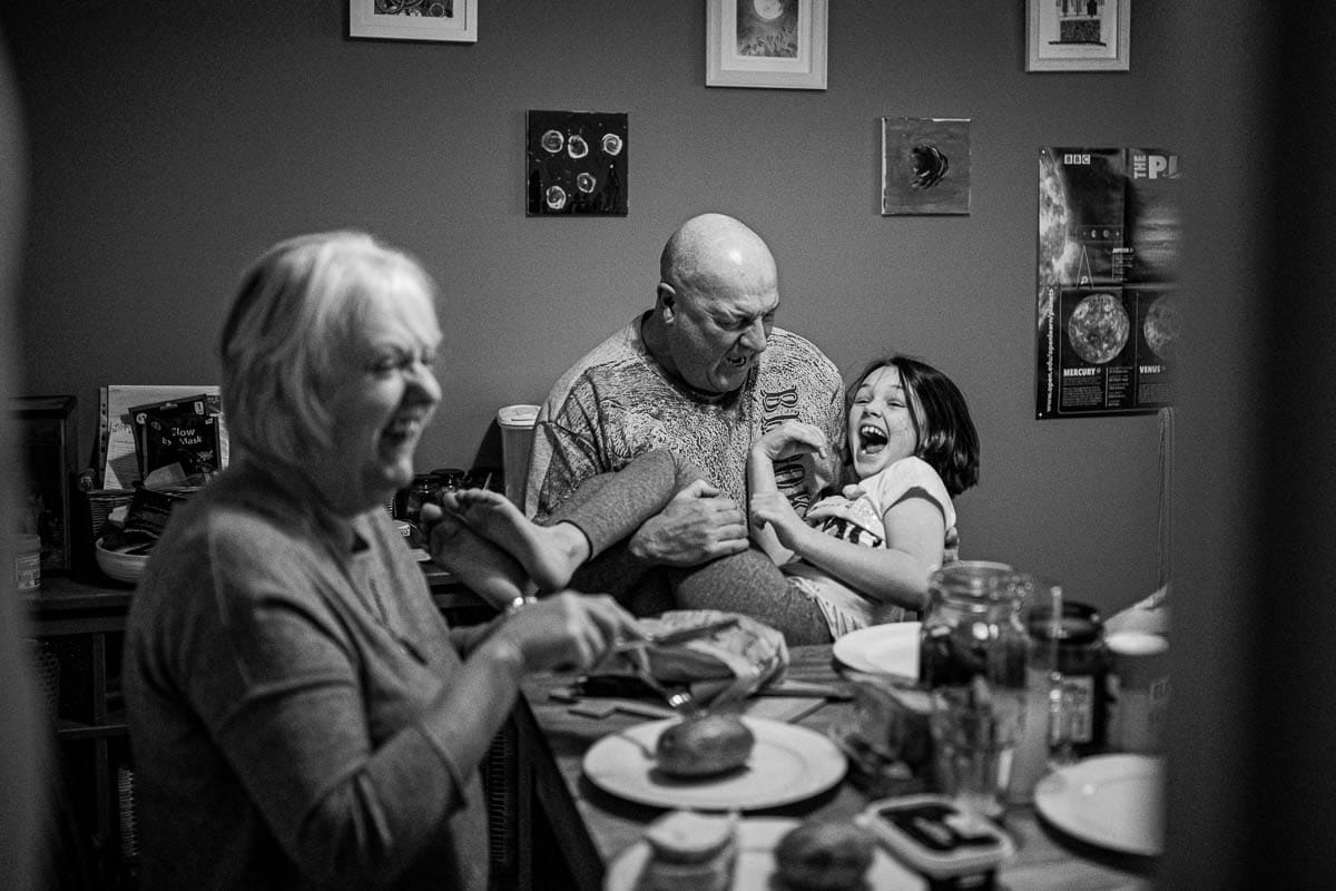 black and white documentary image of a meal with grandparents laughing