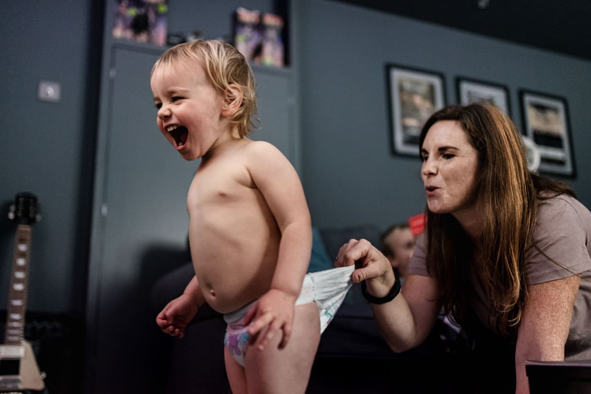 mum pulling laughing baby back by nappy shot by durham documentary family photographer