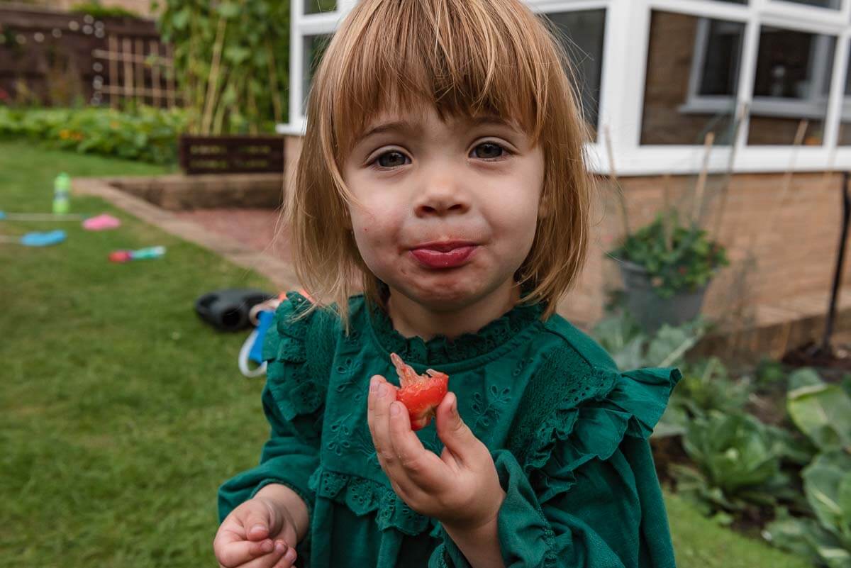young girl in green dress eating a ripe strawberry in county durham